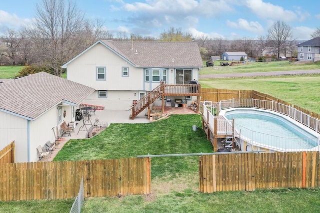 rear view of house with a lawn, a fenced backyard, stairway, a patio, and a wooden deck