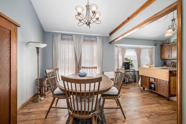 dining space with a chandelier, wood-type flooring, and baseboards