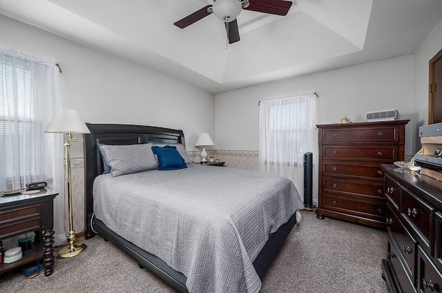 bedroom featuring a tray ceiling, a ceiling fan, and carpet