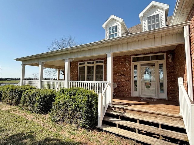 property entrance with brick siding and a porch