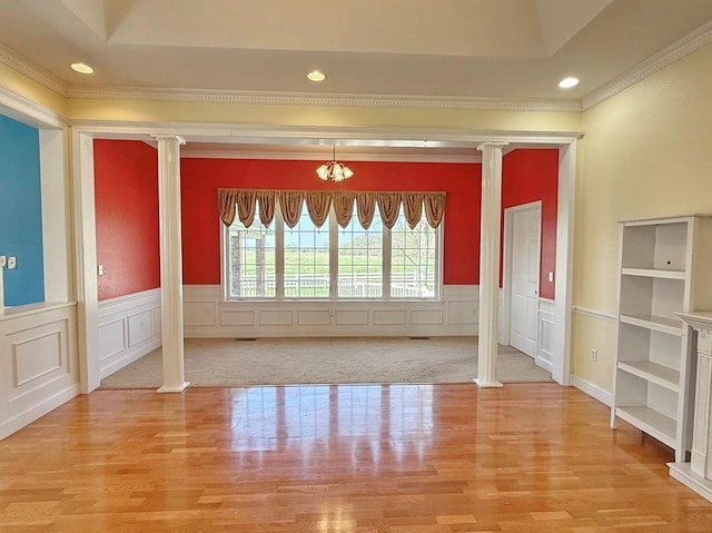 interior space with light wood-type flooring, decorative columns, and wainscoting