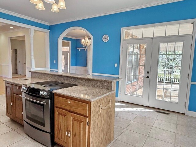 kitchen with a notable chandelier, ornamental molding, light tile patterned floors, stainless steel electric range oven, and arched walkways