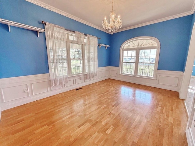 spare room with a chandelier, plenty of natural light, visible vents, and wood finished floors