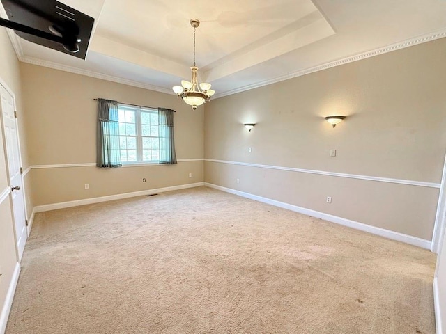 carpeted empty room featuring baseboards, a tray ceiling, and an inviting chandelier