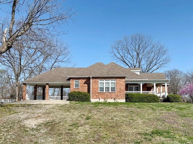 view of front of property with a carport, driveway, a front yard, brick siding, and covered porch
