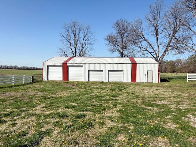 detached garage with fence and a rural view