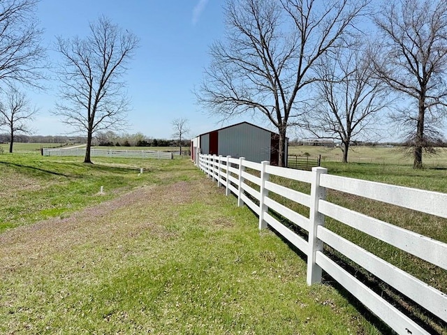 view of yard with a rural view, an outdoor structure, a garage, and a pole building