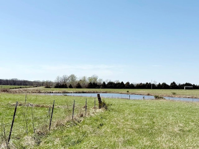 view of yard featuring a water view, fence, and a rural view