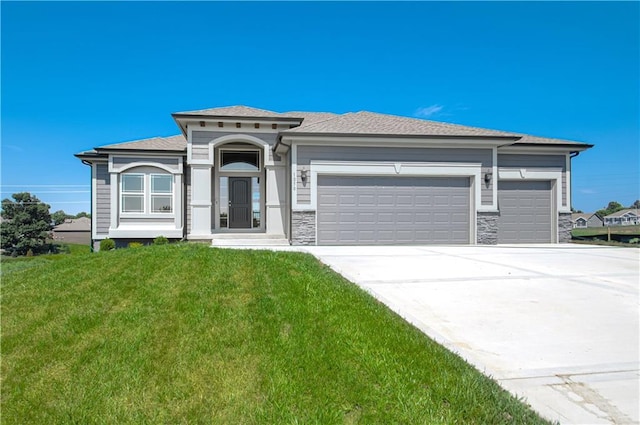prairie-style home featuring stone siding, driveway, a front lawn, and an attached garage