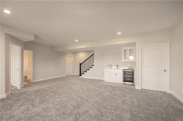 unfurnished living room with recessed lighting, wet bar, light carpet, stairway, and beverage cooler