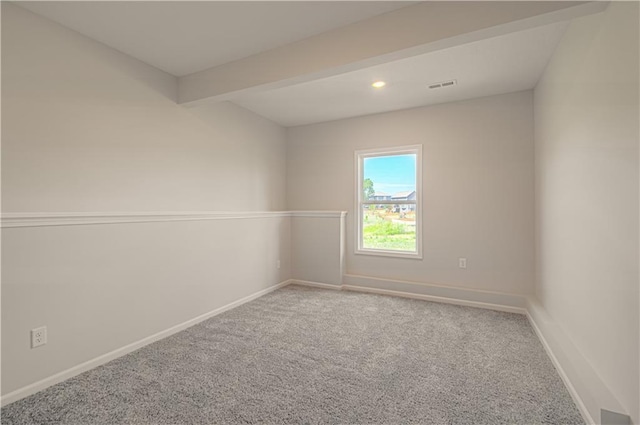 empty room featuring baseboards, carpet floors, visible vents, and beamed ceiling
