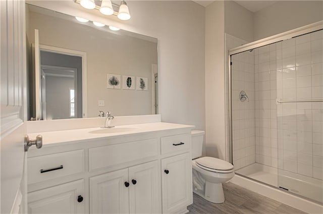 full bath featuring a stall shower, wood finished floors, toilet, and vanity