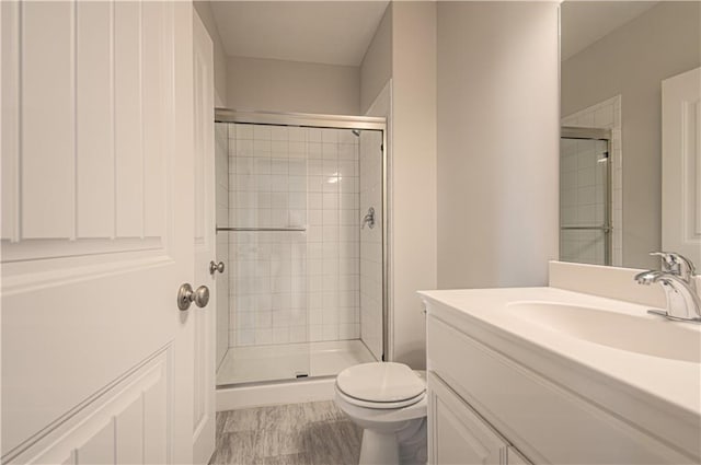 bathroom featuring a stall shower, toilet, and vanity
