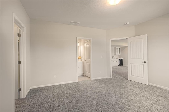 unfurnished bedroom featuring connected bathroom, baseboards, visible vents, and carpet flooring