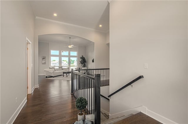 stairway with baseboards, arched walkways, wood finished floors, and ceiling fan