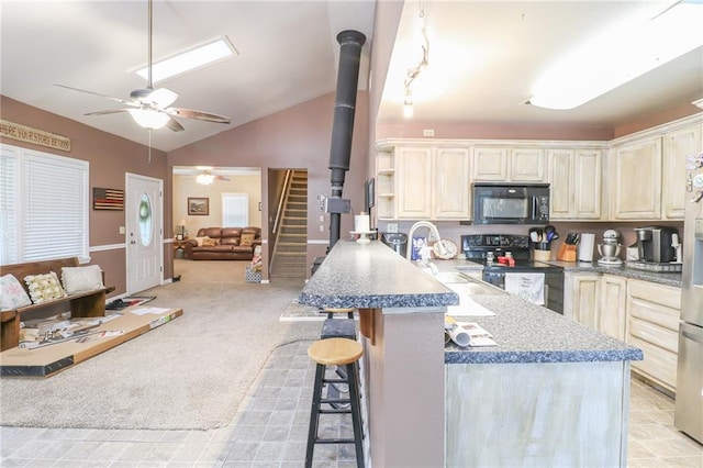 1404 S Market St, Holden, MO 64040 - kitchen featuring black appliances, a kitchen bar, ceiling fan, open floor plan, and lofted ceiling