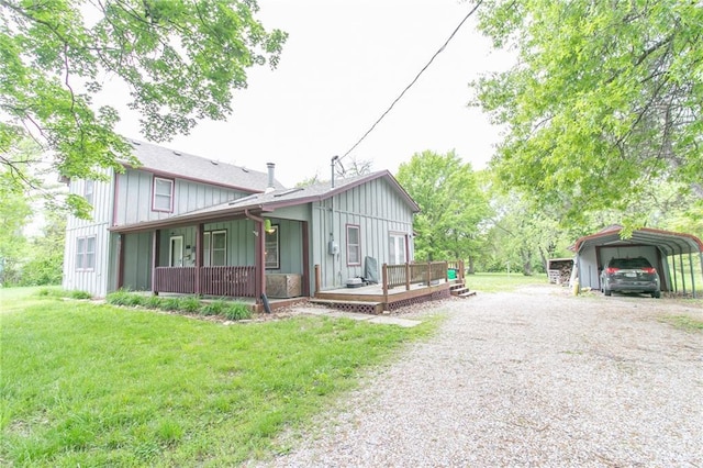 1404 S Market St, Holden, MO 64040 - view of front facade featuring board and batten siding, a detached carport, a front yard, gravel driveway, and a deck