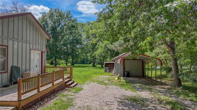 1404 S Market St, Holden, MO 64040 - view of grassy yard featuring a wooden deck, a carport, an outdoor structure, and view of wooded area