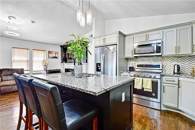 2705 Endicott Ave, Kansas City, KS 66104 - kitchen featuring open floor plan, lofted ceiling, stainless steel appliances, dark wood-style floors, and light stone counters