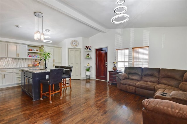 2705 Endicott Ave, Kansas City, KS 66104 - living room featuring lofted ceiling with beams, dark wood-style flooring, and a notable chandelier