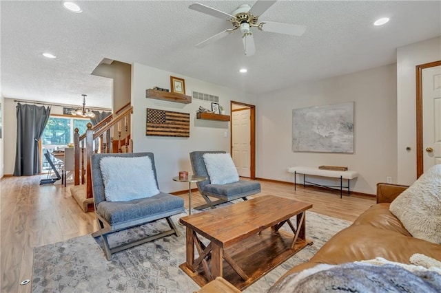 living room featuring a textured ceiling, wood finished floors, recessed lighting, and ceiling fan with notable chandelier