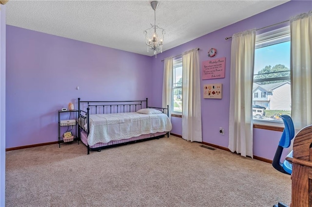 bedroom featuring baseboards, carpet floors, a textured ceiling, and a chandelier