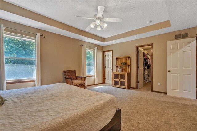 bedroom featuring carpet flooring, a tray ceiling, a spacious closet, and visible vents