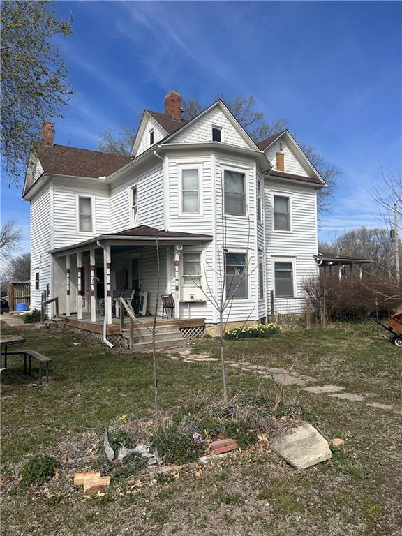 back of property featuring a chimney and covered porch