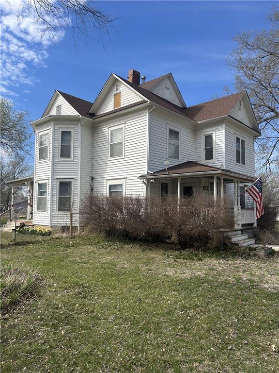 back of property with covered porch and a lawn