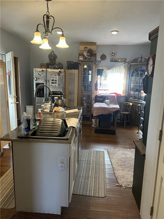 kitchen featuring an inviting chandelier, stainless steel fridge, a center island, and dark wood-style floors