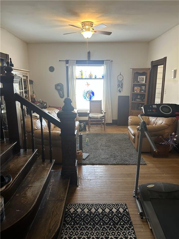 stairs featuring ceiling fan and wood finished floors