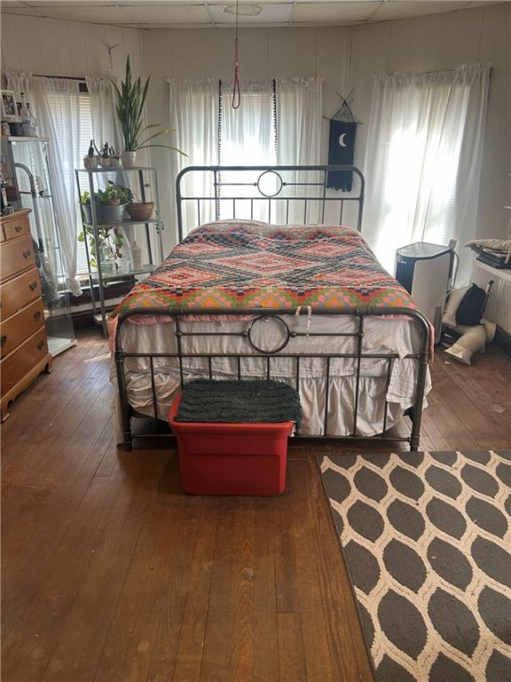 bedroom featuring multiple windows, a drop ceiling, and hardwood / wood-style floors