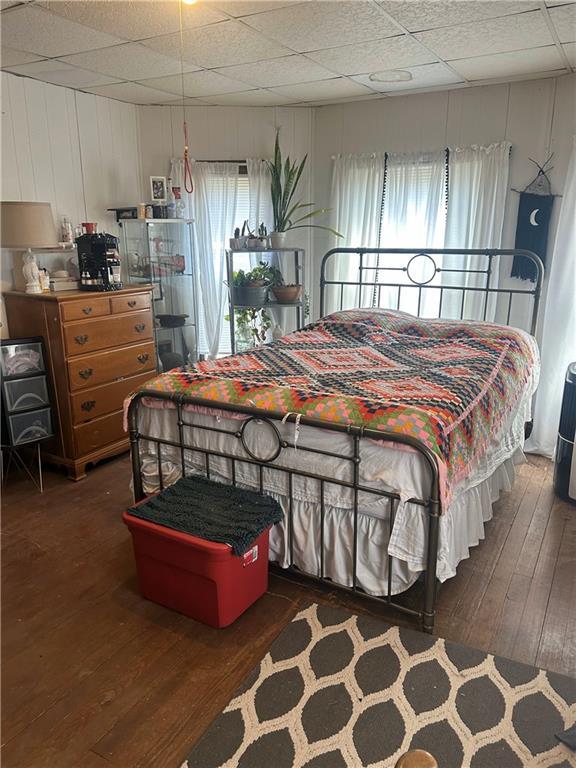 bedroom featuring wood-type flooring and a drop ceiling