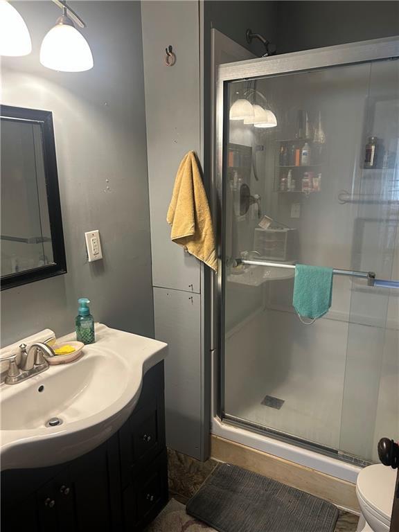 full bath with toilet, a stall shower, and vanity