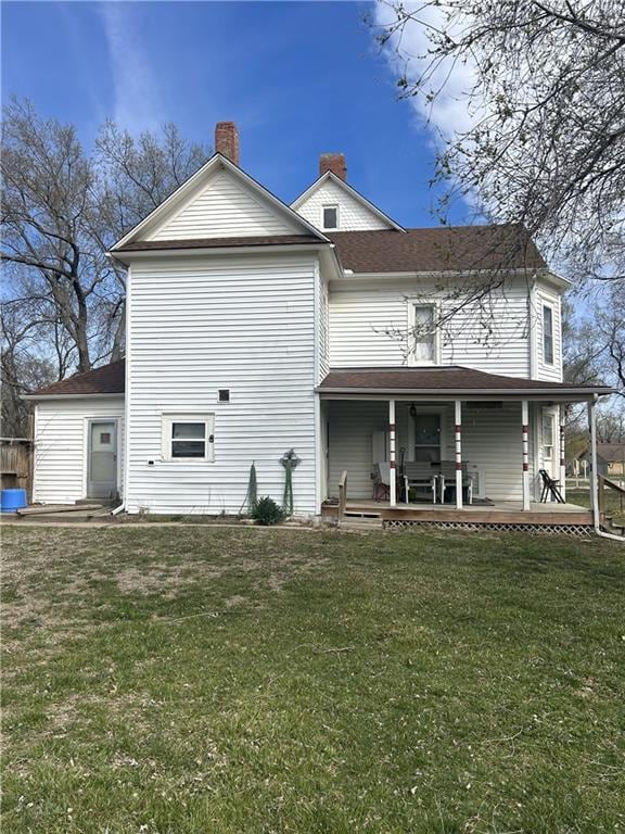 back of property with a chimney and a yard