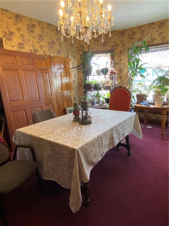 dining room with wallpapered walls, an inviting chandelier, and carpet