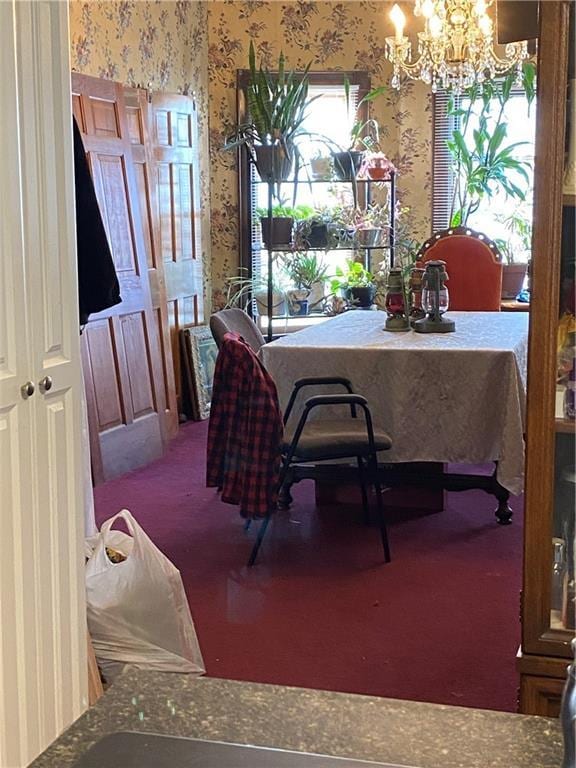 carpeted dining area with wallpapered walls and a chandelier