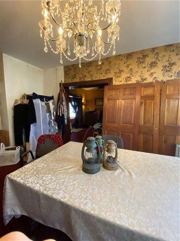 dining room featuring an inviting chandelier and wallpapered walls