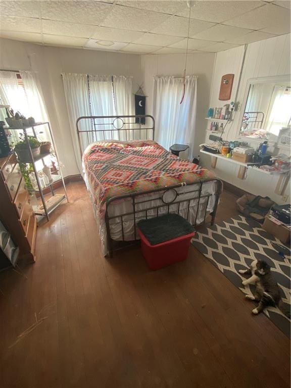 bedroom featuring wood-type flooring, multiple windows, and a drop ceiling