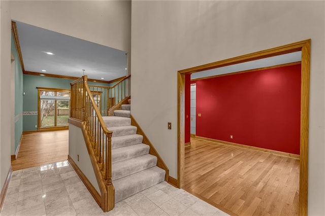 stairs with baseboards, recessed lighting, crown molding, and wood finished floors
