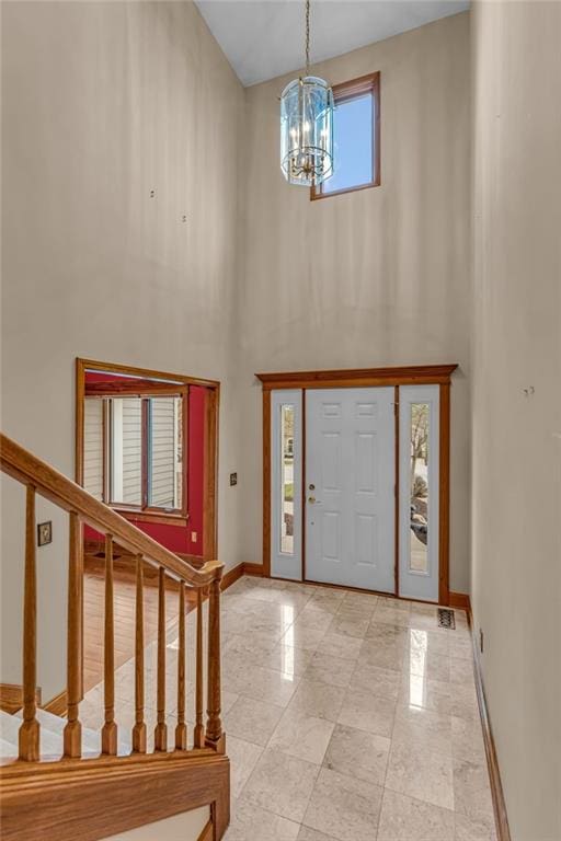 foyer with stairway, baseboards, a high ceiling, and a chandelier