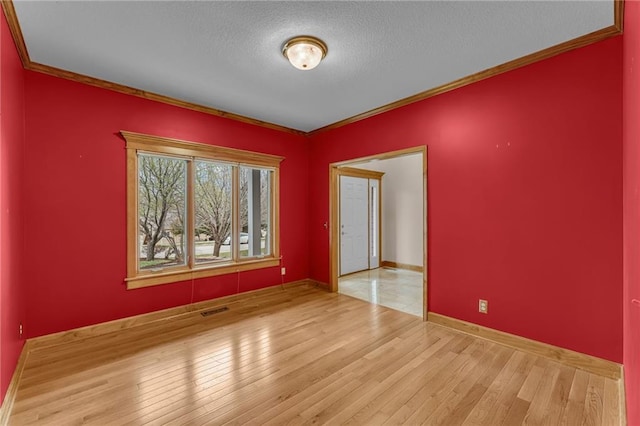 spare room with visible vents, ornamental molding, a textured ceiling, and wood finished floors