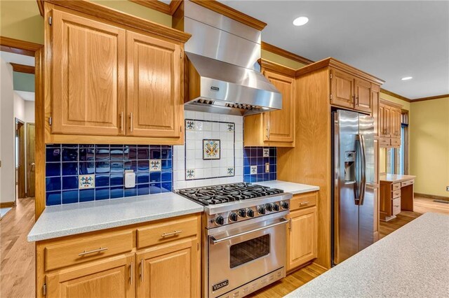 kitchen with wall chimney range hood, appliances with stainless steel finishes, crown molding, and light countertops