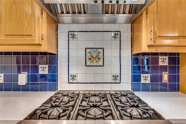 kitchen featuring light countertops, premium range hood, decorative backsplash, and stovetop