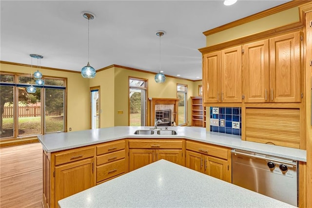 kitchen featuring decorative light fixtures, stainless steel dishwasher, a sink, light countertops, and a peninsula