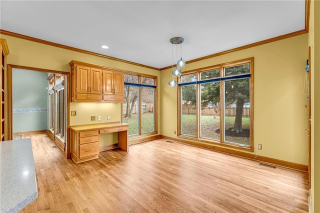kitchen with crown molding, baseboards, visible vents, and a healthy amount of sunlight