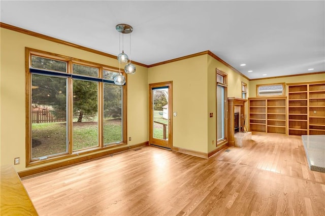 unfurnished dining area featuring crown molding, wood finished floors, baseboards, recessed lighting, and a fireplace with raised hearth