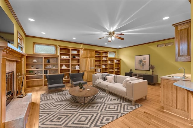 living area with light wood-style floors, ornamental molding, a ceiling fan, and a premium fireplace