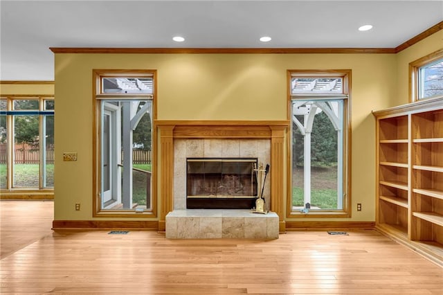 unfurnished living room featuring crown molding, baseboards, wood-type flooring, and a fireplace