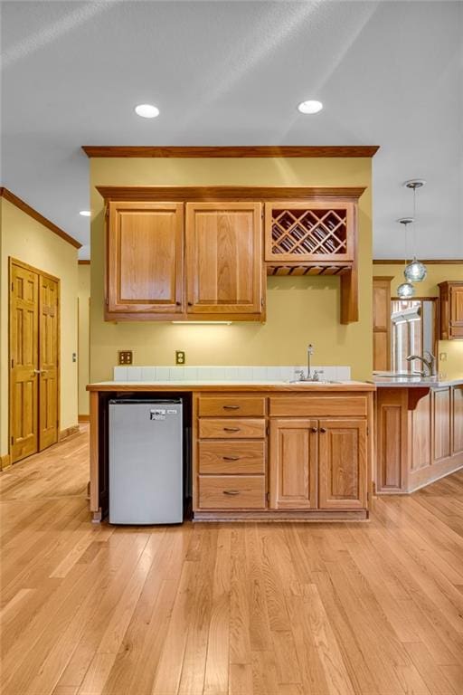 kitchen featuring crown molding, a sink, dishwasher, recessed lighting, and light wood-type flooring